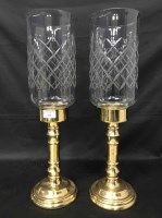 Lot 232 - TWO BRASS CANDLE STANDS with glass tops,...