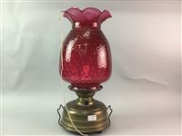 Lot 175 - A BRASS OIL LAMP WITH CRANBERRY SHADE