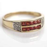 Lot 45 - DIAMOND AND GARNET RING channel set with two...