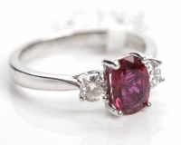 Lot 316 - RUBY AND THREE STONE RING the central oval...