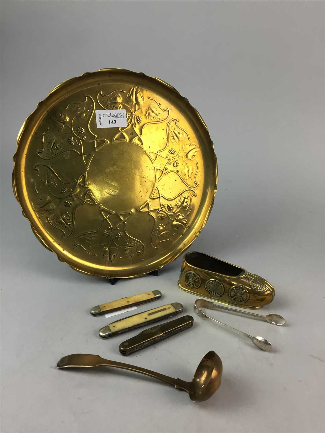 Lot 143 - AN EMBOSSED BRASS TRAY, SUGAR TONGS, POCKET KNIVES AND SOUVENIR SPOONS