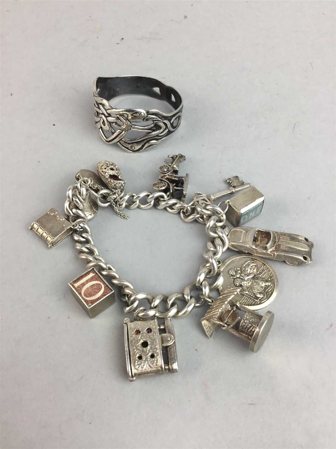 Lot 128 - A SILVER CHARM BRACELET AND A SILVER NAPKIN RING
