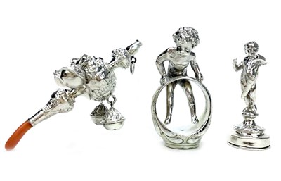 Lot 946 - A CONTINENTAL SILVER FIGURE OF A BOY WITH A SEAL AND RATTLE