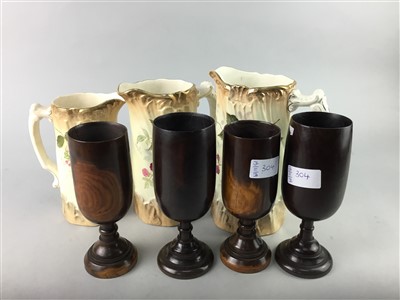 Lot 304 - A GRADUATED SET OF THREE FLORAL DECORATED JUGS AND TREEN GOBLETS