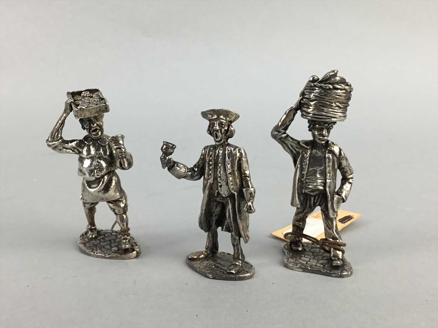 Lot 131 - A SILVER FIGURE OF A MARKET SELLER AND TWO OTHER SIMILAR FIGURES