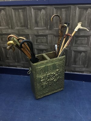 Lot 316 - A BRASS EMBOSSED STICK STAND CONTAINING WALKING STICKS AND UMBRELLAS