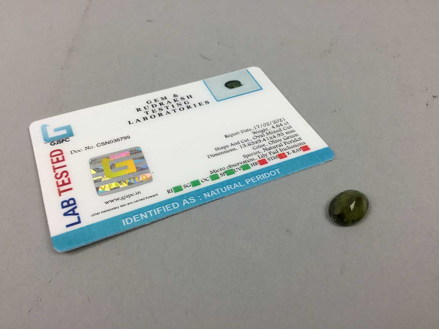 Lot 60 - **CERTIFICATED UNMOUNTED PERIDOT, oval mixed...