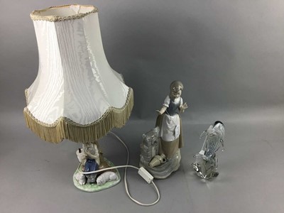 Lot 280A - A NAO FIGURE OF A GIRL BY A WATER FOUNTAIN, A FIGURAL TABLE LAMP AND A GLASS DOLPHIN