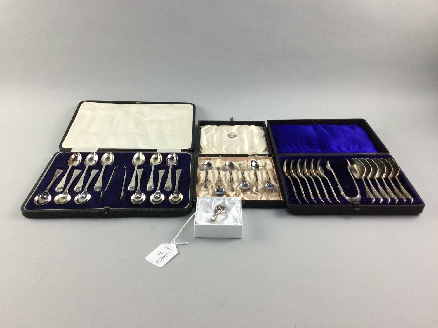Lot 21 - A SILVER NAPKIN HOLDER, ALONG WITH THREE CASED FLATWARE SETS