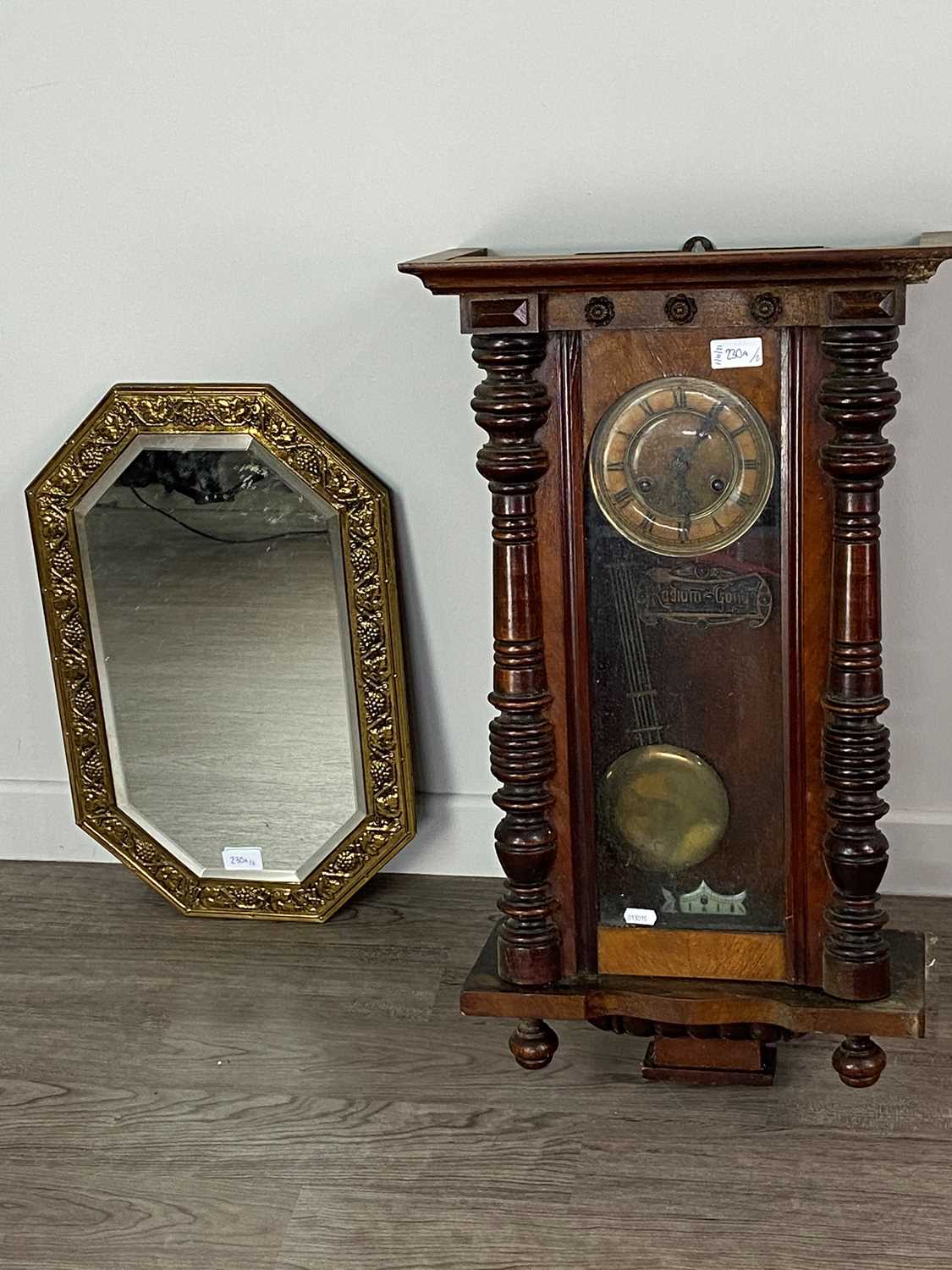 Lot 230 - AN OAK WALL CLOCK AND A BRASS EMBOSSED WALL MIRROR
