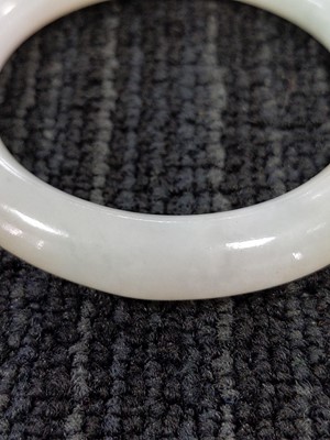 Lot 1088 - A CHINESE PALE GREEN HARDSTONE BANGLE