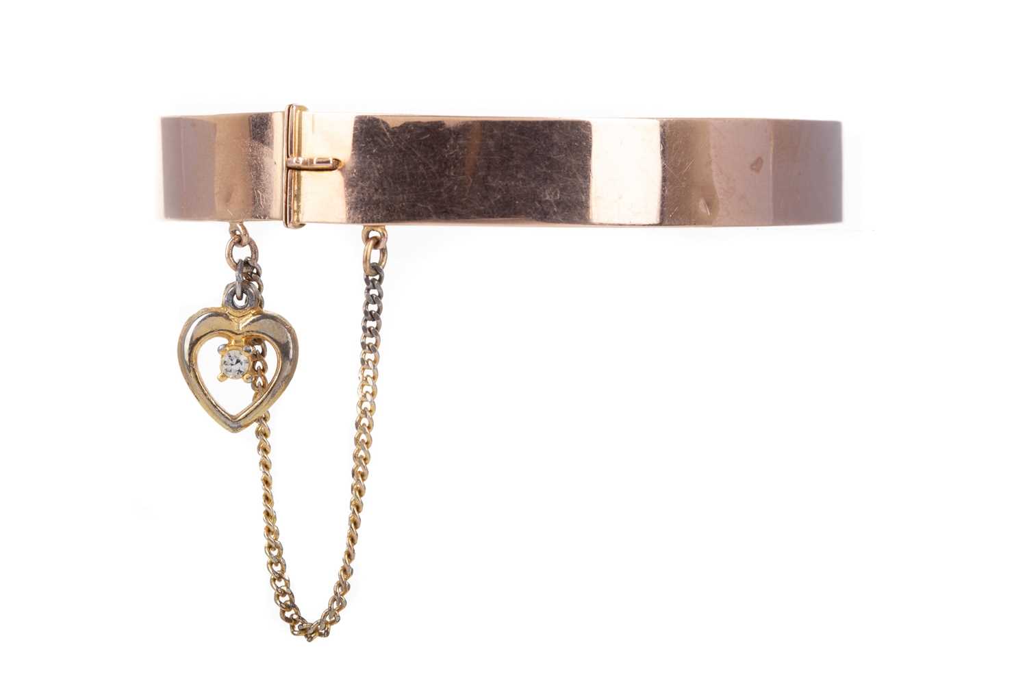 Lot 686 - A GOLD BANGLE WITH YELLOW METAL HEART CHARM