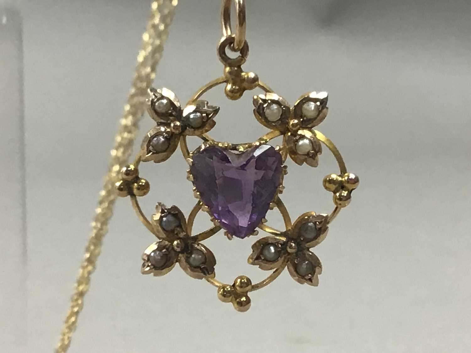 Lot 34 - AN EDWARDIAN NINE CARAT GOLD AMETHYST AND SEED PEARL PENDANT ON GOLD CHAIN