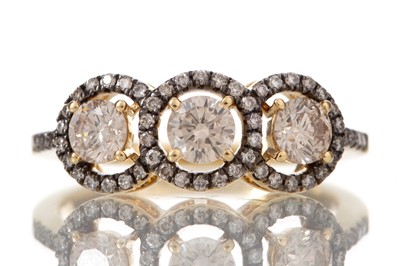 Lot 469 - COGNAC DIAMOND THREE STONE HALO RING