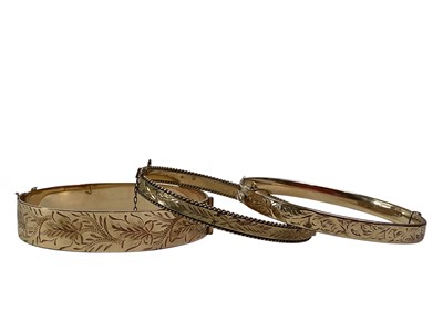 Lot 21 - THREE ROLLED GOLD BANGLES