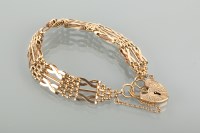 Lot 1298 - NINE CARAT GOLD BRACELET with a heart shaped...