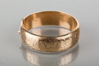 Lot 1783 - NINE CARAT GOLD BANGLE engraved with scrolling...