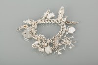 Lot 1114 - SILVER CHARM BRACELET with charms including a...