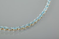 Lot 1383 - TOPAZ SET BRACELET formed by oval blue topaz,...