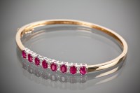 Lot 1219 - RUBY AND DIAMOND BANGLE with oval cut rubies...