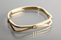 Lot 1198 - NINE CARAT GOLD BANGLE with bow motif,...