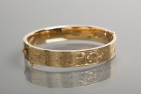 Lot 1210 - NINE CARAT GOLD BANGLE engraved with a...