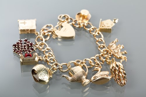 Lot 457  A 9ct gold charm bracelet suspending twenty
