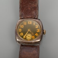 Lot 1091 - SILVER TRENCH WATCH with a cushion shaped case,...