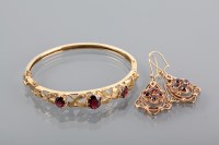 Lot 1255 - GARNET SET BANGLE with three oval garnets,...