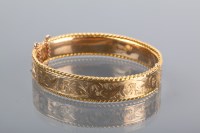 Lot 1336 - NINE CARAT GOLD BANGLE with scrolling foliate...