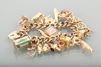 Lot 1223 - NINE CARAT GOLD CHARM BRACELET with various...