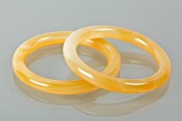 Lot 1200 - TWO YELLOW HARDSTONE BANGLES possibly jade,...